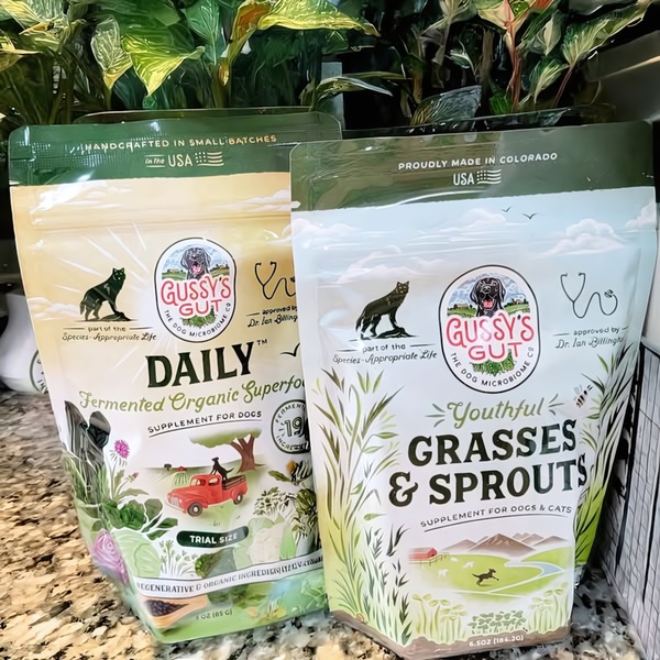 A high-clarity 1:1 shot of two Gussy's Gut supplement bags placed side-by-side in front of green foliage, emphasizing product variety.